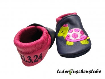 Lederpuschen dunkelblau-pink mit Namen links und Datums rechte Ferse dunkelblau sowie Stickerei Schildi 2 pink-rosa-hellgrün Schmetterlinge 